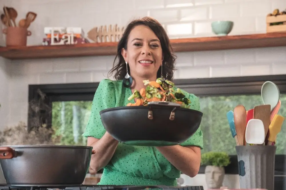 Marina finalizando legumes salteados na panela
